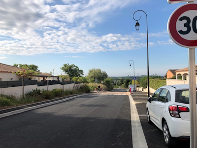 Photo d'une route nouvellement goudronnée qui est en zone 30 avec une voiture garée sur le bas côté