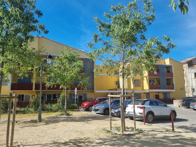 Photo d'un bâtiment jaune avec un parking devant avec des voitures