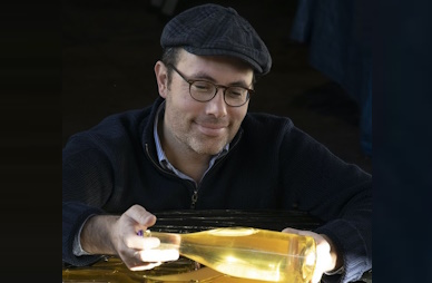 Photo d'une personne tenant une bouteille de vin blanc sur un fond noir