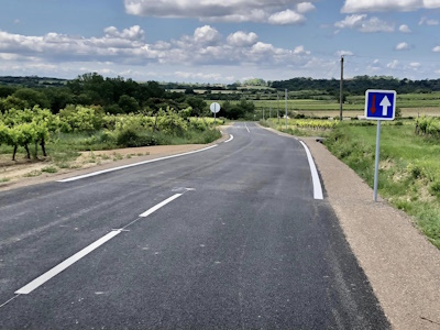 Photo d'une route à la sortie du village avec une forêt au loin